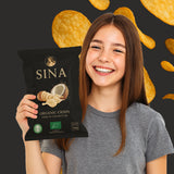 Person holding a SINA organic crisps packet with crisps in the background